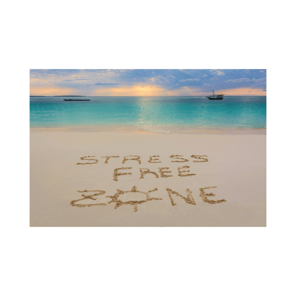 The words "Stress-Free Zone" written in the sand on a beach during a serene sunset.