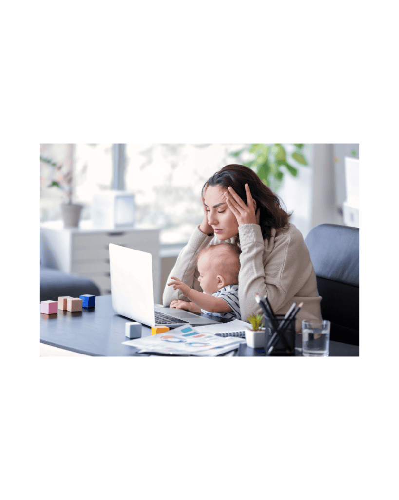 A stressed mother working on a laptop while holding her baby, struggling to balance work and childcare.
