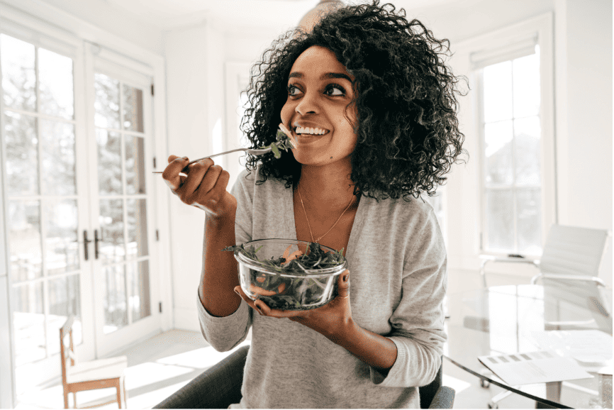 Woman enjoying a fresh salad in a bright kitchen