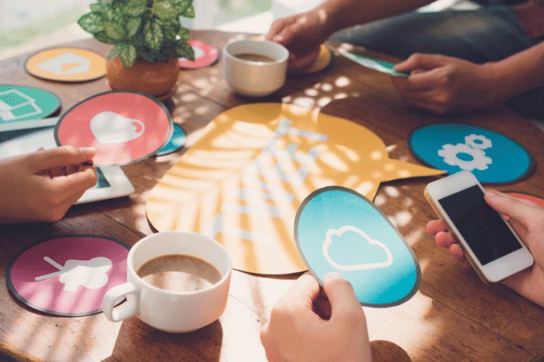 People holding smartphones and digital icons at a table with coffee