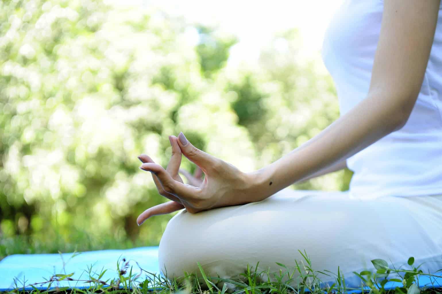 Woman wears white doing meditation in the park