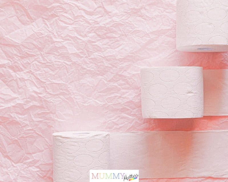 Toilet paper rolls arranged on a pink textured background for a clean, minimalist look.