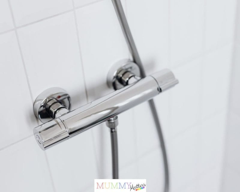 Modern chrome shower faucet on white tiled wall, elegant and clean design.