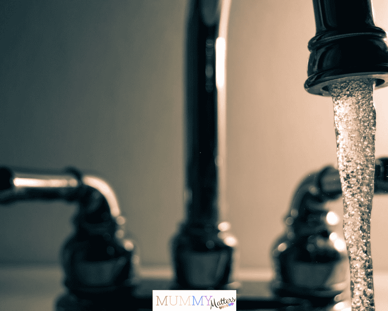 A detailed shot of water flowing from a steel faucet, ideal for themes on cleanliness or plumbing.