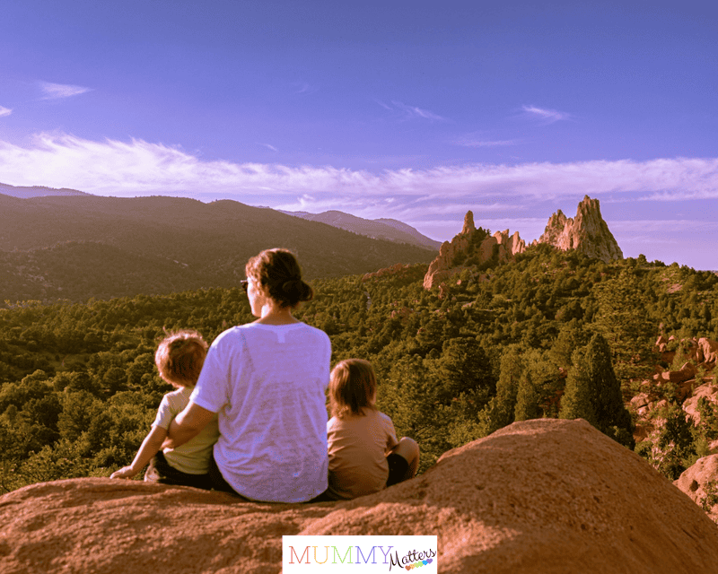 a woman and two children sitting on top of a rock on a family adventure