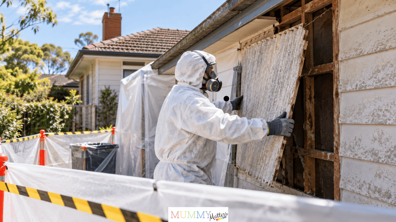 Professional asbestos removal worker wearing protective clothing and a respirator while removing old fibro sheeting from an Australian home.