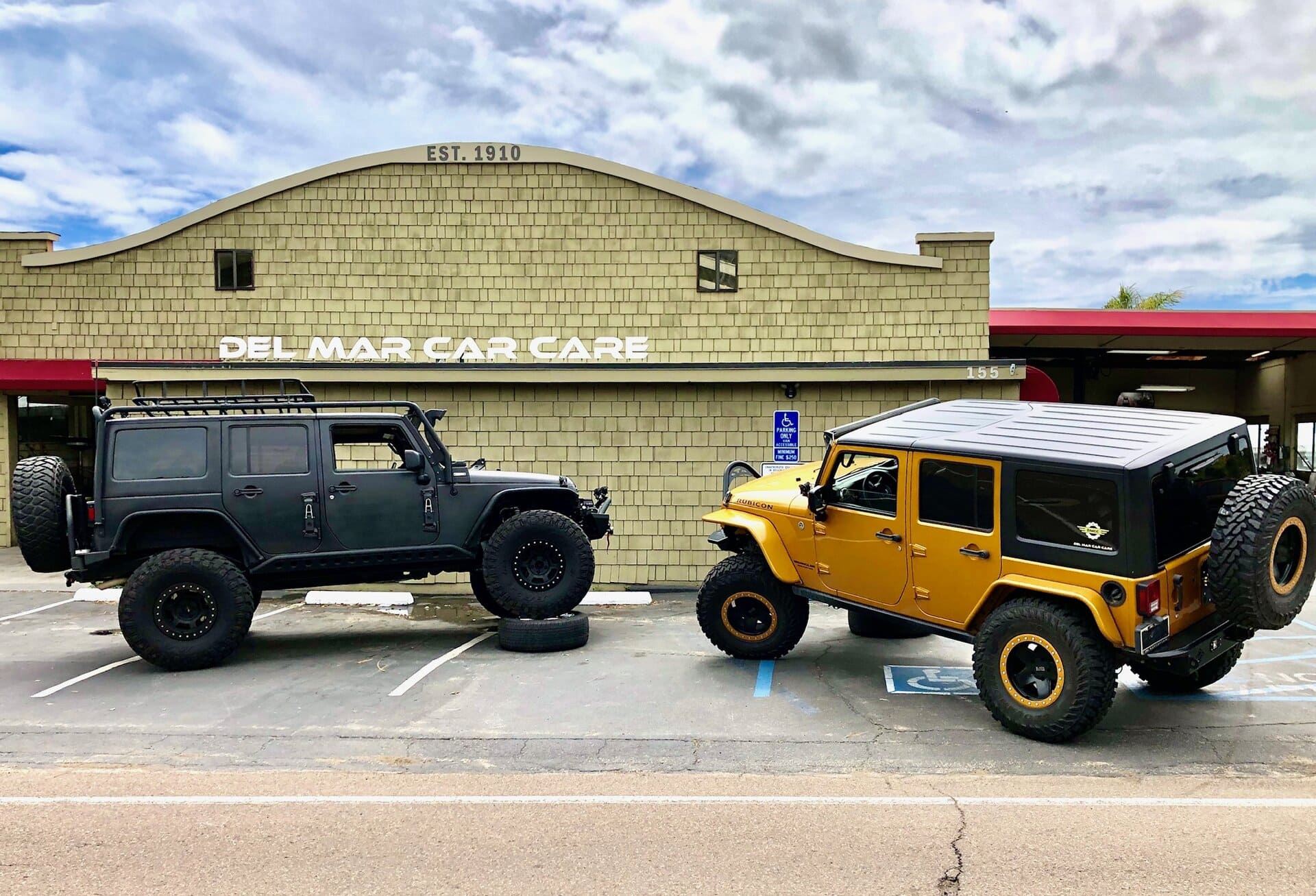 Two rugged off-road vehicles parked in front of Del Mar Car Care, a trusted auto service center specializing in vehicle maintenance and repairs in Del Mar.