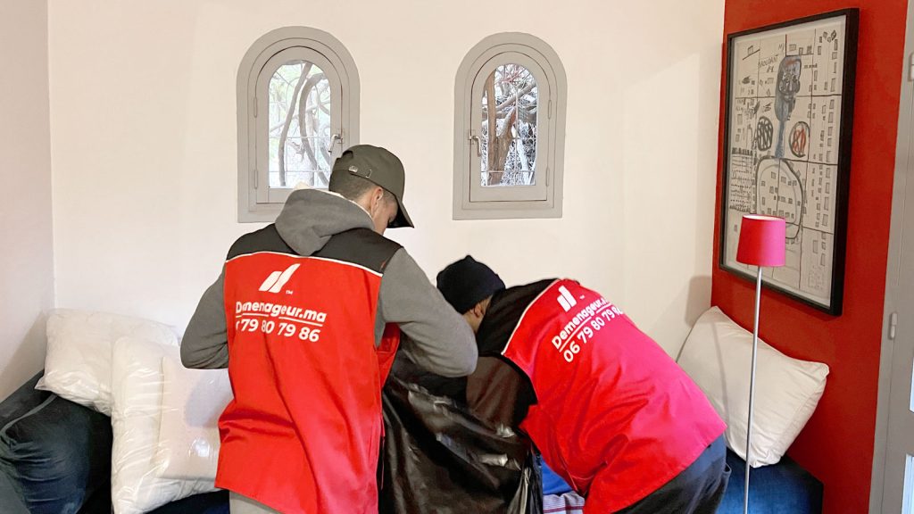 Des déménageurs qui emballent des oreillers dans des sacs dans une chambre d'une villa à Marrakech