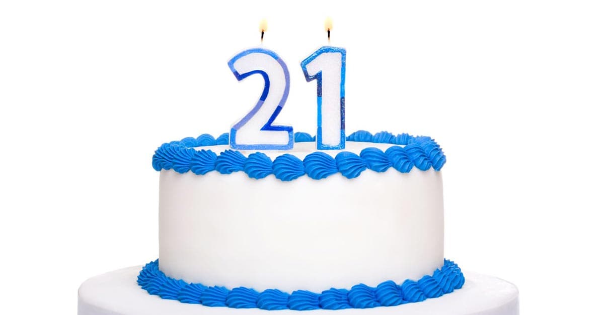 White cake with blue icing and lit 21 candles—ideal for celebrating reaching the age to audition as a Disneyland princess.