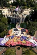 Hundreds of guests create a giant Mickey Mouse shape in front of Disneyland’s Sleeping Beauty Castle—an unforgettable park moment.