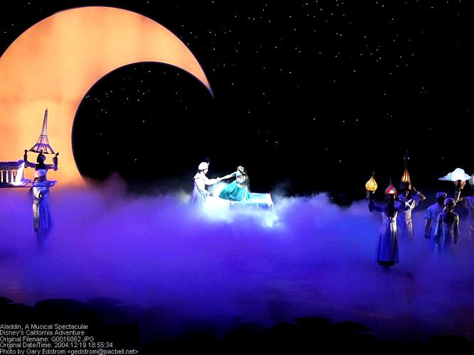 Aladdin and Jasmine soar on their magic carpet above clouds, with a glowing crescent moon and stars—a Disney Parks classic scene.