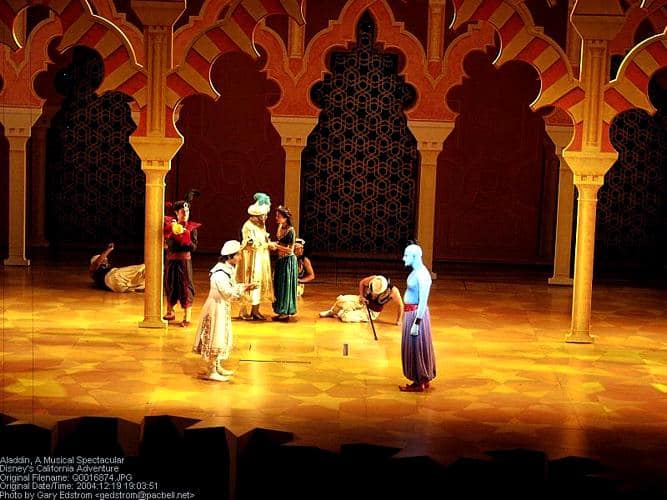 Genie dazzles onstage in Aladdin at Disney's Hollywood Studios, with ornate arches and vibrant Broadway-style magic.