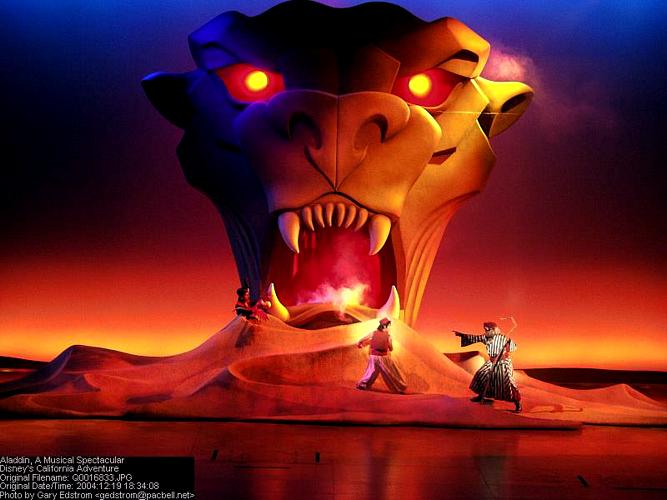 Entertainers perform on stage before a glowing Lion King's larger-than-life head with blazing eyes, reminiscent of Disney magic.