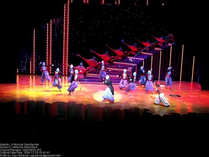 Aladdin and friends dazzle on stage with flying carpets and vibrant costumes against a magical starry backdrop at Disney Parks.