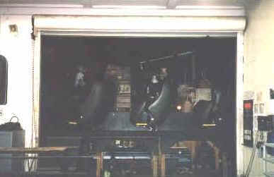 Backstage Disney: shadowy room with control panels and machinery glimpsed through an open service door, evoking hidden park magic.
