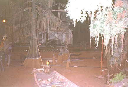 Moody, mossy swamp lit by a lantern; trees and weathered wood evoke Disneyland’s secret after-hours backstage magic.