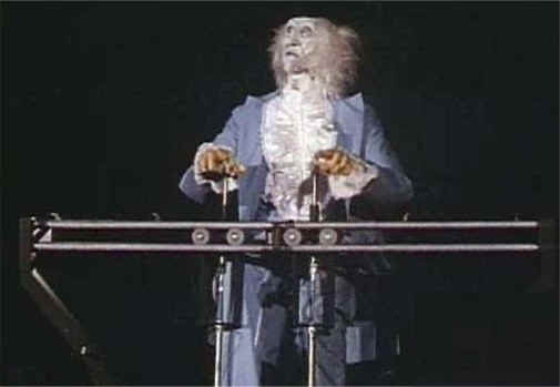 A performer in a ruffled shirt and blue coat works the onstage levers, capturing the behind-the-scenes wonder of Disneyland shows.