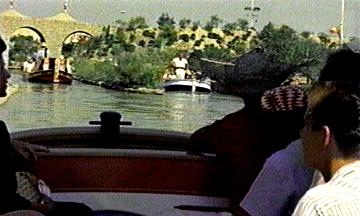 Guests enjoy a magical boat ride along Disneyland’s river, passing under iconic stone arches and lush trees in the park.