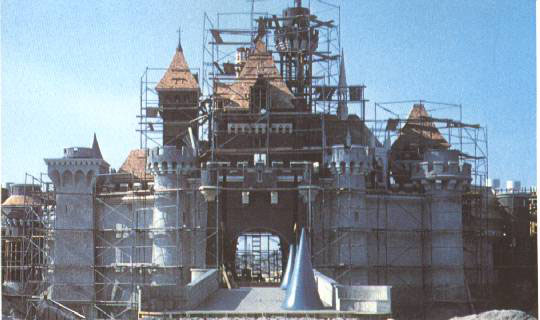 Sleeping Beauty Castle being built, surrounded by scaffolding, set against a clear blue sky at Disneyland.