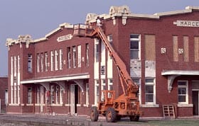 A cherry picker lifts workers to restore vintage brick windows, like prepping a new stage for the park’s next big attraction.