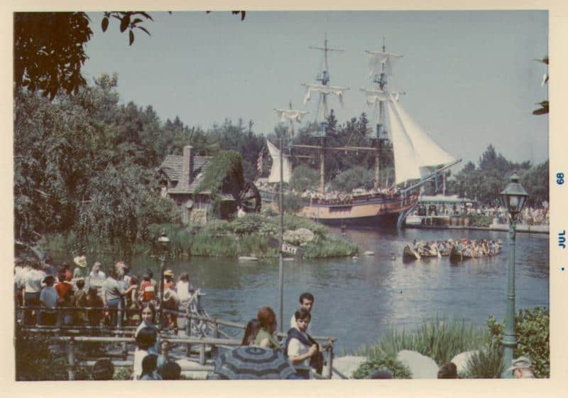 Disneyland, July 1958: A bustling riverfront scene with the iconic Mark Twain Riverboat and canoes packed with guests.