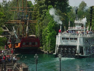 The Mark Twain Riverboat and Sailing Ship Columbia pass each other on the lively Rivers of America in Disneyland’s Frontierland.
