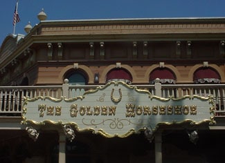 The Golden Horseshoe sign with ornate trim atop its classic Western facade in Disneyland’s Frontierland.