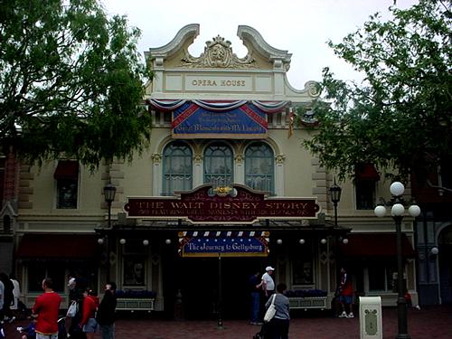 The Walt Disney Story Opera House at Disneyland adorned with red, white, and blue banners, guests strolling by.