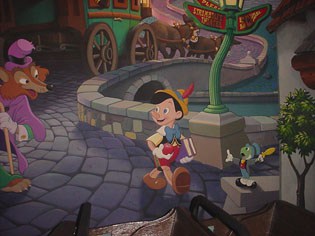 Pinocchio strolls Main Street U.S.A. with Jiminy Cricket as Honest John and a fairytale carriage appear in the background.