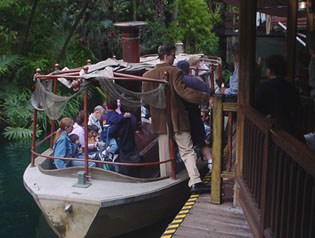 Guests board the Jungle Cruise at Adventureland, surrounded by tropical foliage and themed wooden docks.