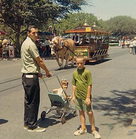 Families enjoy a sunny day by a vintage horse-drawn trolley at the amusement park, ready for classic fun and adventure.