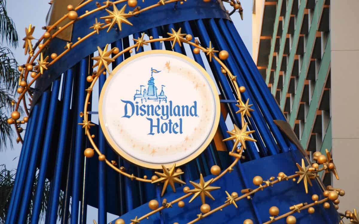 Iconic Disneyland Hotel sign adorned with gold stars and sleek blue accents, set against a backdrop of the resort building.