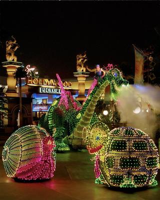 Snail and turtle floats dazzle Main Street, their lights shimmering before a massive green dragon in the Electrical Parade.