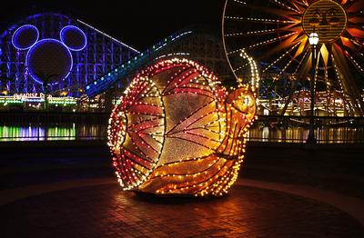 The dazzling illuminated snail float sparkles with vibrant lights during Disneyland’s Main Street Electrical Parade at night.