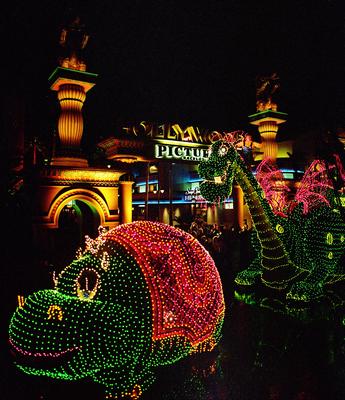 Elliott the Dragon from the Main Street Electrical Parade glows with lights as he floats past Hollywood Pictures at Disneyland.