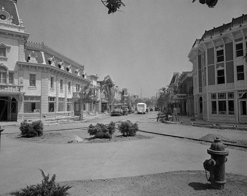 Classic black-and-white shot of Disneyland’s Main Street, empty, with charming vintage storefronts and a fire hydrant up front.