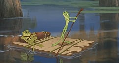 Tiana and Naveen as frogs float down a river on a makeshift raft, Tiana paddling spiritedly while Naveen relaxes.