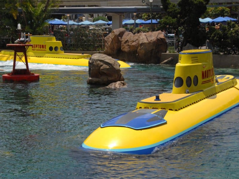 Disneyland’s iconic yellow submarines glide through the vibrant lagoon, surrounded by rocks and lush themed landscaping.