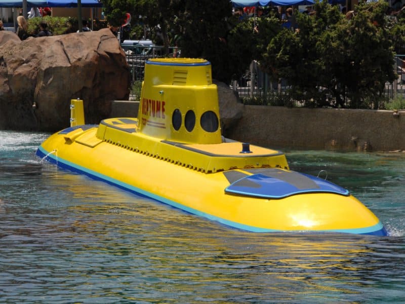 The iconic yellow Disneyland submarine floats by lush rocks and greenery in the park's classic Submarine Voyage attraction.
