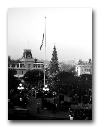 Vintage black and white photo of a Christmas tree and flagpole in a lively plaza, echoing Main Street’s magical holiday spirit.
