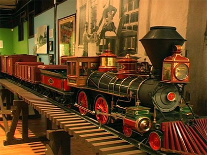 A classic model train with bright red wheels on display at the theme park's railroad history attraction.