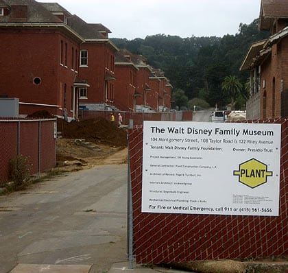 View of The Walt Disney Family Museum sign and red brick buildings at a lively Disney site under construction.