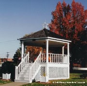 A white gazebo with steps pops amid vibrant autumn leaves, creating storybook magic like a scene from Main Street, U.S.A.