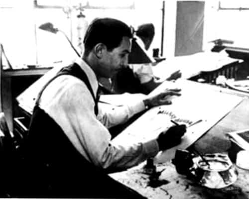 An Imagineer sketches at a drafting table in a Disney studio, echoing classic Walt Disney scenes, with another artist nearby.