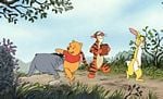 Winnie the Pooh, Tigger, Rabbit, and Eeyore stroll through Hundred Acre Wood at Disneyland, sharing a magical adventure.