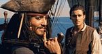 A swashbuckling pirate grins for guests on a themed ship, with a friendly crew member joining the immersive sea adventure.