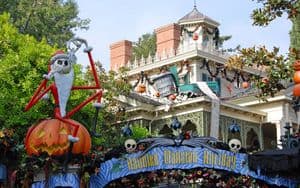 Halloween-themed Haunted Mansion wallpaper featuring Jack Skellington, pumpkins, festive garland, and eerie trees at Disneyland.