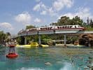The Disneyland Resort monorail glides above the Submarine Lagoon and lush landscaping under bright skies, ideal for photo galleries.