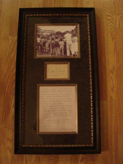 Shadowbox display featuring a vintage Walt Disney black-and-white photo, his signed card, and handwritten letter on wooden flooring.