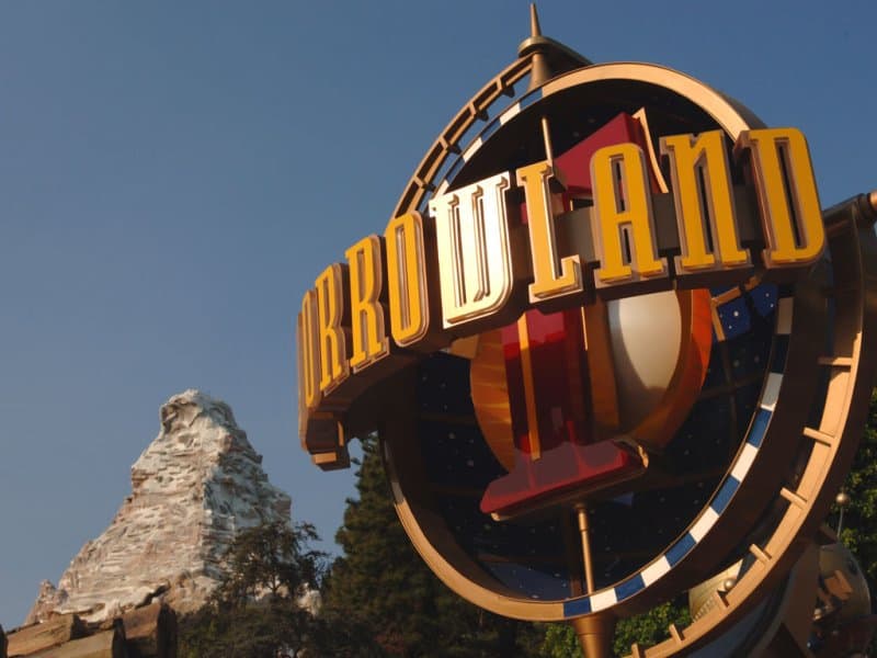 Tomorrowland entrance at Disneyland with the iconic Matterhorn in the background beneath a vibrant blue sky.